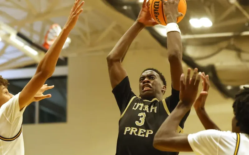 A.J. Dybantsa, wearing a Utah Prep jersey with the number 3, leaps to shoot a basketball as three defenders attempt to block him during a high school game.