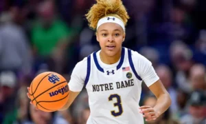 Hannah Hidalgo of Notre Dame dribbles the basketball during a game, wearing the team's white jersey with 'Notre Dame' written across the chest, showcasing focus and determination.