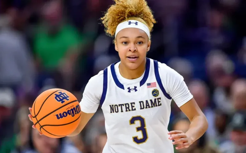 Hannah Hidalgo of Notre Dame dribbles the basketball during a game, wearing the team's white jersey with 'Notre Dame' written across the chest, showcasing focus and determination.